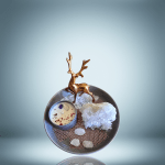 A decorative setup featuring a golden reindeer figurine, a candle with rose petals and crystals, a large clear quartz cluster, and three smaller quartz stones arranged on a gray plate with a textured mat