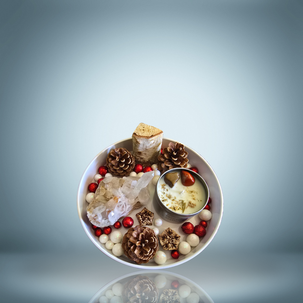 A decorative arrangement featuring a quartz crystal cluster, pinecones, red and white decorative balls, a small log piece, a candle with herbs and stones inside, and small dried flowers or seeds