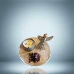 A decorative set featuring a glittering angel figurine, a scented candle in a tin, and a super dark red quartz cluster, all arranged on tulle