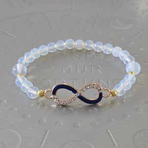 Translucent opalescent bead bracelet with small gold spacer beads and an infinity symbol charm, half encrusted with rhinestones and half dark blue