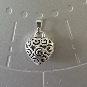 Silver-toned brass heart pendant with intricate swirl design, 1 inch.