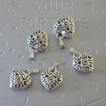 Silver-toned brass heart pendant with intricate swirl design, 1 inch.