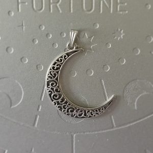 A brass crescent moon pendant with intricate filigree designs, measuring 2 inches in size.