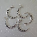 A brass crescent moon pendant with intricate filigree designs, measuring 2 inches in size.