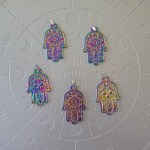 A titanium pendant shaped like the Hamsa hand with an iridescent finish, featuring intricate patterns.