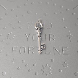 A brass key-shaped pendant with an intricate cross cutout near the bit.