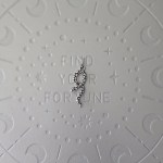 A metallic snake-shaped pendant displayed against a textured background.