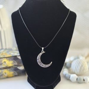 A delicate crescent moon pendant necklace called Aura Moon Necklace, featuring intricate filigree designs and paired with a sleek black cord.