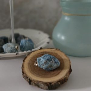 A rough blue apatite pendant with a silver clasp, hanging from a sturdy Korean wax black cord, displayed on a white background.