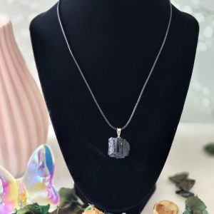 A rough tourmaline pendant displayed on a black velvet display.