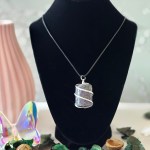 A rough purple garnet necklace displayed on a black velvet stand.