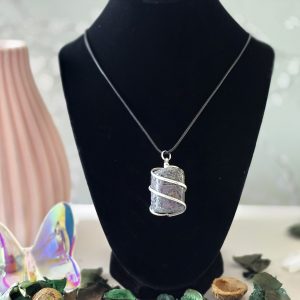 A rough purple garnet necklace displayed on a black velvet stand.