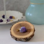 A stunning amethyst pendant with a gold bail displayed a piece of wood.