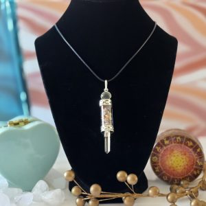 A beautifully crafted chakra stone pendulum necklace displayed on a black velvet display.