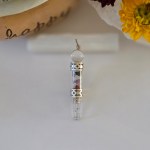 A stunning chakra stone pendulum pendant displayed on a piece of natural selenite stick.