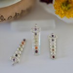 Five stunning clear quartz chakra pendants displayed on a piece of natural selenite stick.