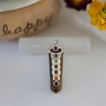 A stunning tiger eye chakra pendant displayed on a piece of natural selenite stick.