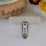 A stunning amethyst chakra pendant displayed on a piece of natural selenite stick.