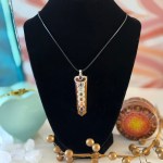 A stunning tiger eye chakra necklace displayed on a piece of natural selenite stick, featuring a 22-inch Korean Wax Black cord.