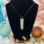 A stunning aventurine chakra necklace displayed on a black velvet display, featuring a 22-inch Korean Wax Black cord.