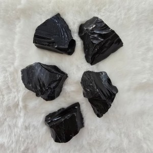 A collection of raw Black Obsidian stones, displaying their glossy black surfaces and natural volcanic texture.